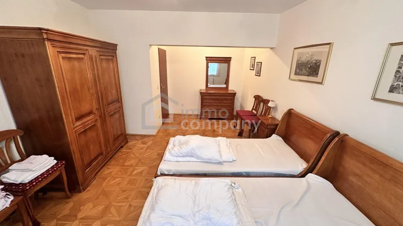 Schlafzimmer mit zwei Einzelbetten, traditionellen Holzmöbeln und klassischem Parkettboden.