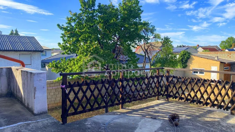 Dachterrasse mit Holzzaun und Blick auf die umliegenden Dächer und Bäume.