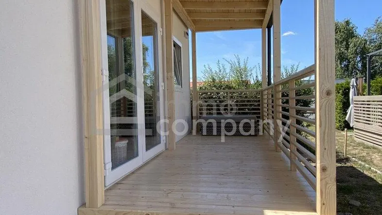 Überdachte Holzterrasse mit Treppe und Geländer, ideal für entspannte Stunden im Freien.