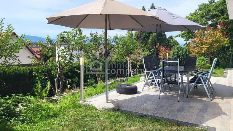 Gemütliche Terrasse mit Gartenmöbeln und Sonnenschirmen, umgeben von viel Grün und Weitblick.