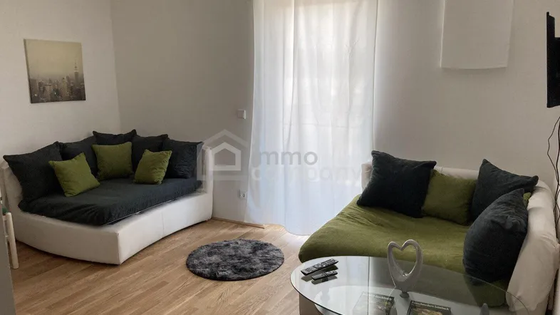 Gemütliches Wohnzimmer mit zwei Sofas, einem Glastisch und hellem Holzboden.