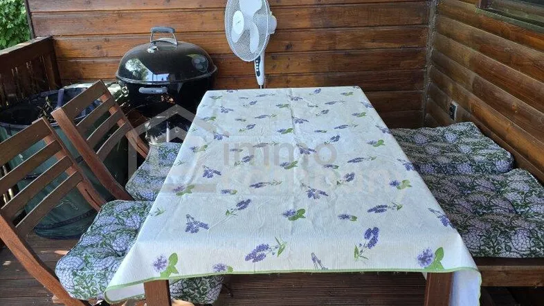 Gemütliche Holzterrasse mit Esstisch, Stühlen und Grillbereich, ideal für entspannte Stunden im Freien.