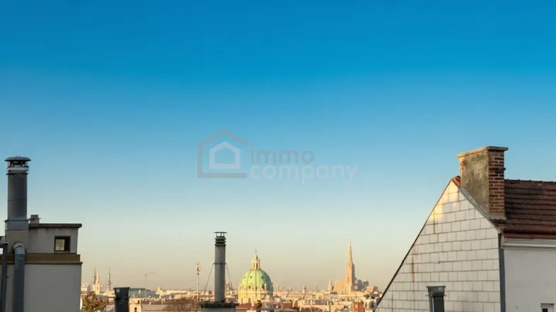 Panoramablick über die Dächer der Stadt mit historischen Gebäuden und einem klaren blauen Himmel.
