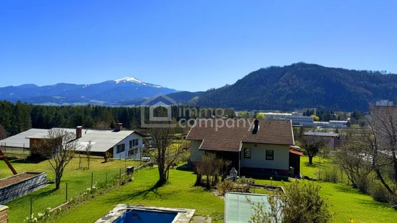 Weitläufiger Gartenbereich mit Pool und Blick auf die umliegende Berglandschaft.