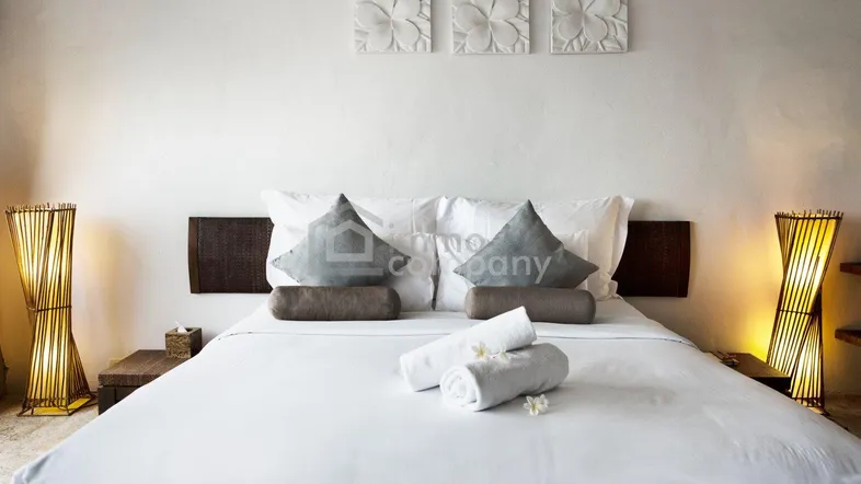 Helles Schlafzimmer mit großem Doppelbett, minimalistischer Dekoration und indirekter Beleuchtung durch Bambuslampen.