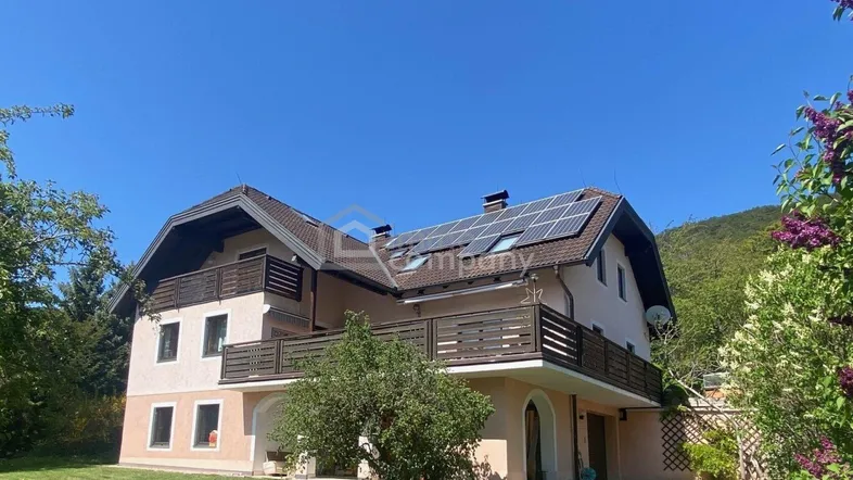 Großes Einfamilienhaus mit mehreren Balkonen, Photovoltaikanlage auf dem Dach und Garten.