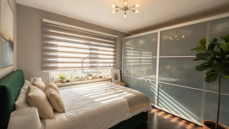 Helles Schlafzimmer mit dunklem Holzboden, großem Fenster und Schiebetürenschrank.