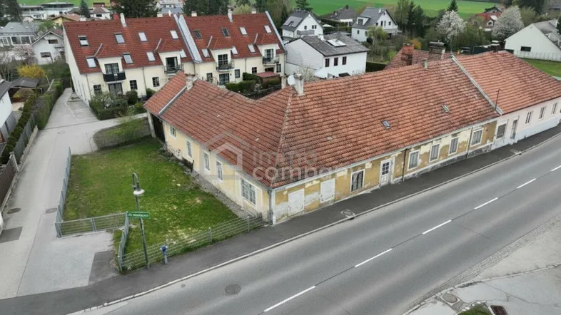 Luftaufnahme eines ländlichen Anwesens mit mehreren Gebäuden und angrenzender Straße.