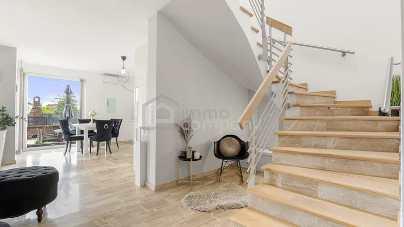 Moderner Eingangsbereich mit heller Holztreppe und Blick auf den Essbereich mit Zugang zum Garten.