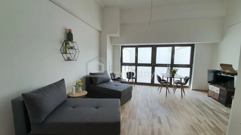 Helles Wohnzimmer mit Holzboden, bequemen Sofas und einem kleinen Essbereich am Fenster.