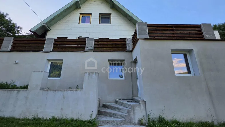 Vorderansicht des Hauses mit Treppe zum Eingang und Giebeldach.