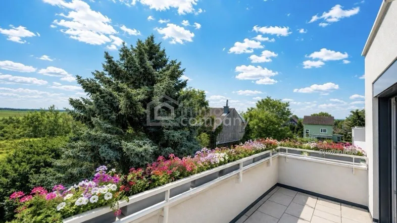 Geräumiger Balkon mit Blumenkästen und weitem Blick ins Grüne unter blauem Himmel.