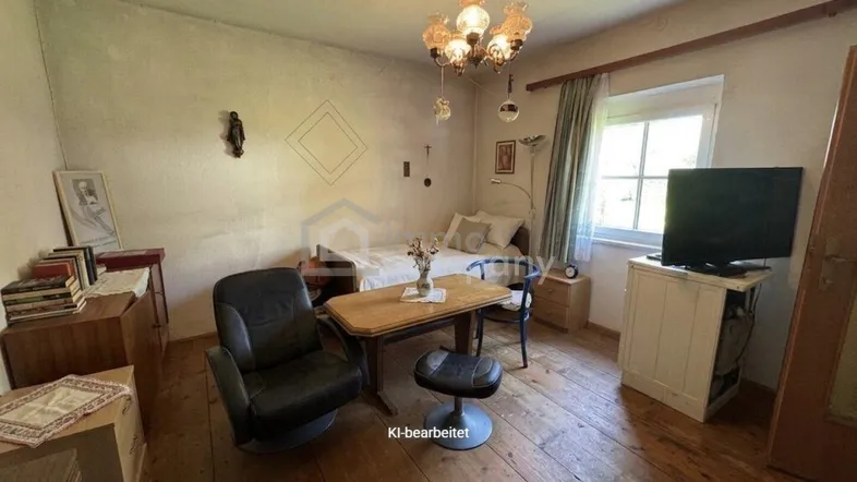 Rustikales Schlafzimmer mit Holzboden, einem Einzelbett und einem kleinen Tisch am Fenster.