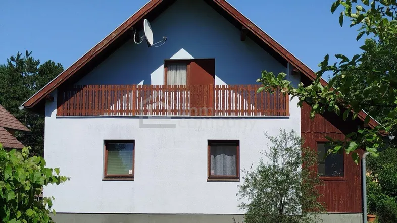 Frontansicht eines Einfamilienhauses mit Satteldach, Balkon und weißer Fassade.