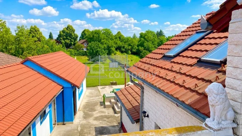 Blick vom Balkon auf das Grundstück mit weiteren Gebäuden und viel Grün.
