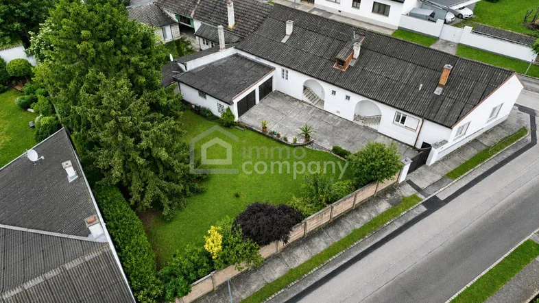 Luftaufnahme des Anwesens mit großem Garten, Einfahrt und angrenzenden Gebäuden.