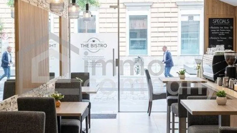 Heller Restaurantbereich mit großen Glasfronten, die viel Tageslicht hereinlassen, und einer modernen Theke.