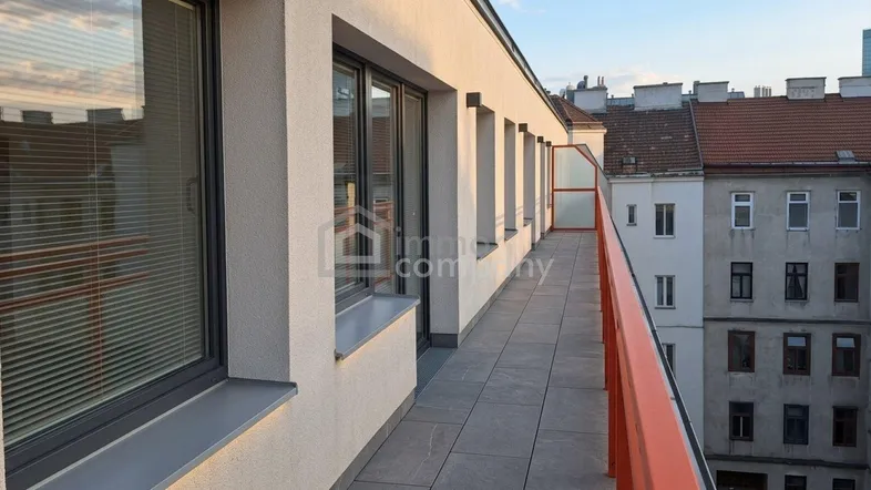 Langer, schmaler Balkon mit Fliesenboden und Blick auf die umliegenden Gebäude.