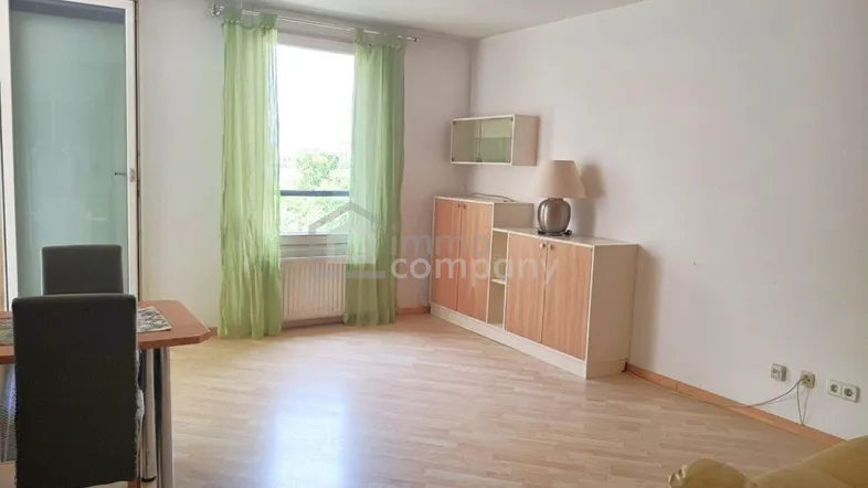Heller Wohn- und Essbereich mit hellem Holzboden, Fenster und Zugang zu einem Balkon oder Terrasse.