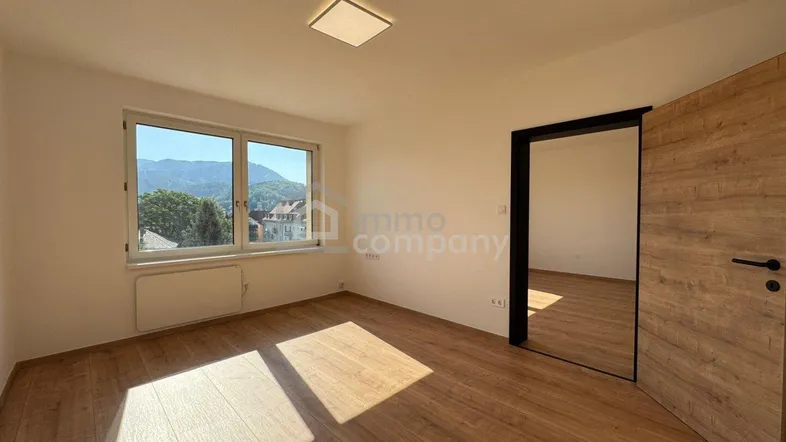 Helles, unmöbliertes Zimmer mit Holzboden und Blick auf die umliegende grüne Landschaft.