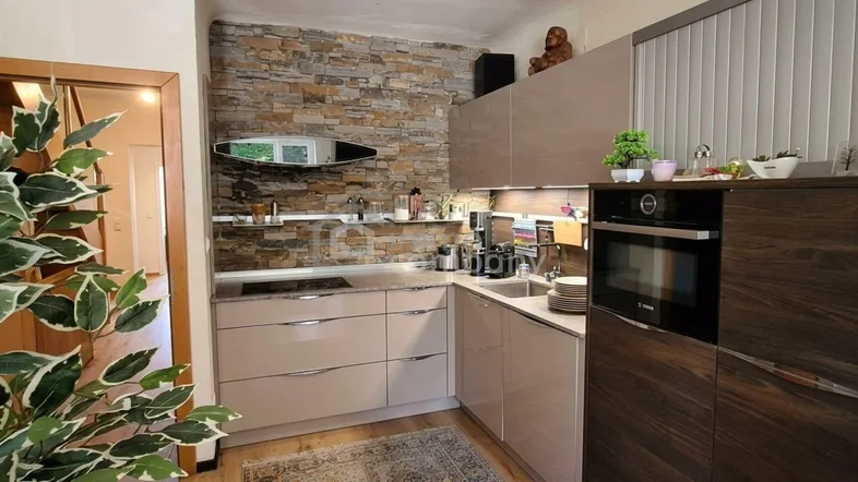 Moderne Küche mit Steinwand, integrierten Geräten und viel Stauraum in eleganten Schränken.