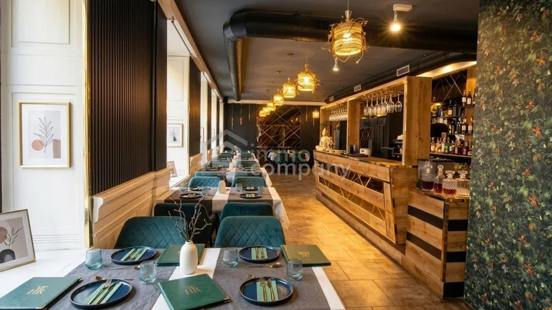 Modernes Restaurant mit elegant gedeckten Tischen, einer stilvollen Bar und großen Fenstern, die viel Tageslicht hereinlassen.