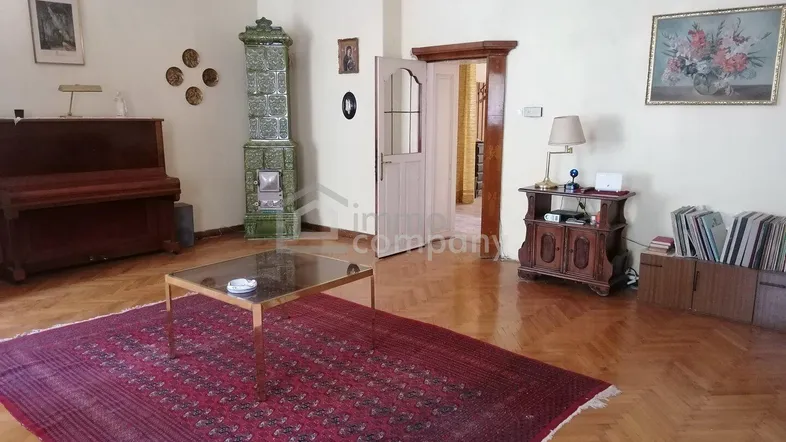 Geräumiges Wohnzimmer mit traditionellem Kachelofen, Parkettboden und klassischer Einrichtung.