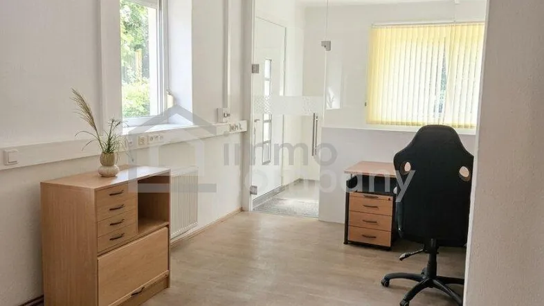 Helles Büro mit Laminatboden, einem Fenster mit Blick ins Grüne und moderner Büroeinrichtung.