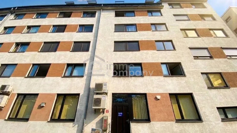 Fassade eines Mehrfamilienhauses mit mehreren Etagen und Fenstern unter blauem Himmel.