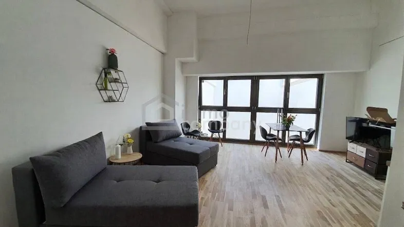 Helles Wohnzimmer mit Holzboden, bequemen Sofas und großen Fenstern, die viel Licht hereinlassen.