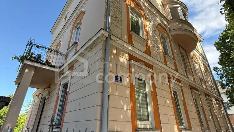 Historisches Gebäude mit verzierter Fassade, Erker und kleinem Balkon unter blauem Himmel.