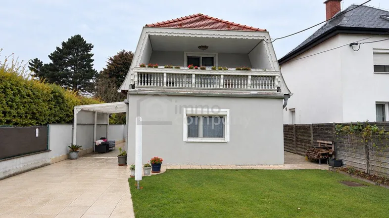 Einfamilienhaus mit Mansarddach, Vorgarten, gepflasterter Einfahrt und Carport.