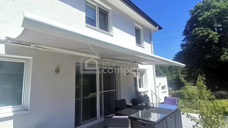 Geräumige Terrasse mit Markise und Gartenmöbeln, ideal für entspannte Stunden im Freien.