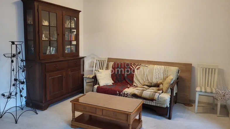 Gemütliches Wohnzimmer mit traditionellem Holzschrank, Sofa und Couchtisch auf hellem Fliesenboden.