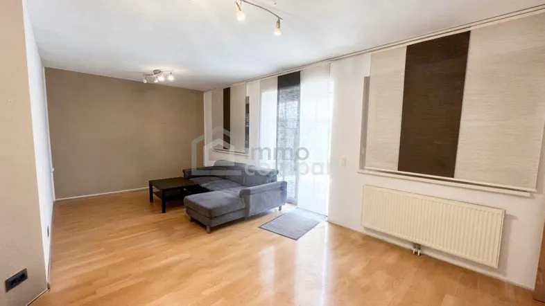 Helles Wohnzimmer mit Parkettboden, beiger Wandfarbe und Zugang zu einem Außenbereich.