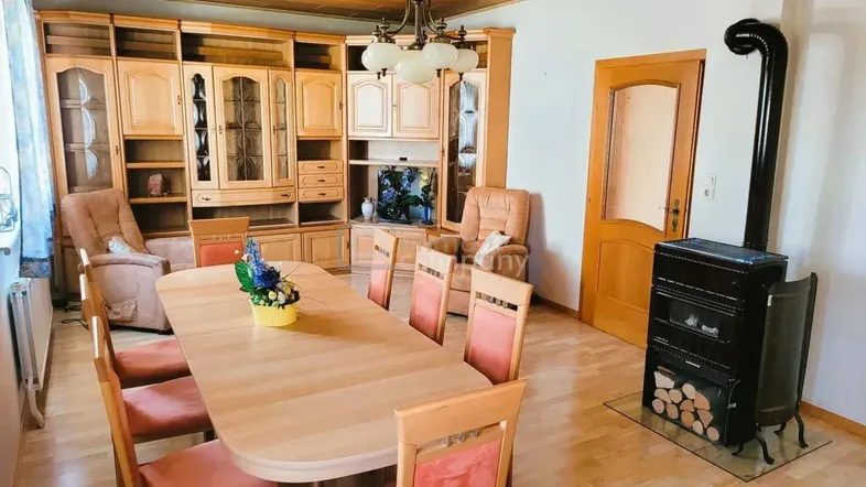 Traditioneller Wohn-Essbereich mit Holzmöbeln, großem Wandschrank und gemütlichem Holzofen.