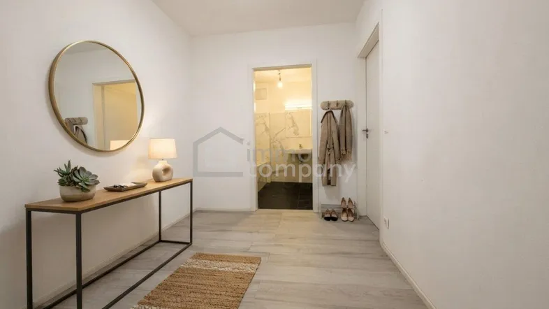 Heller Eingangsbereich mit modernem Spiegel, Konsole und Zugang zu einem Badezimmer.