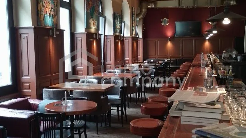 Geräumiger Barbereich mit Holzboden, hohen Bogenfenstern und gemütlichen Sitzgelegenheiten, ideal für Gäste.