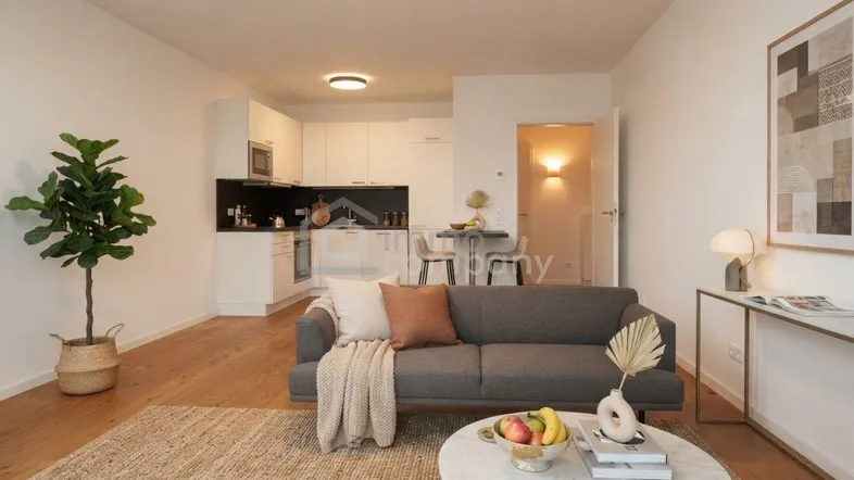 Helles Wohnzimmer mit offener Küche, Holzboden und moderner Einrichtung, ideal für geselliges Beisammensein.