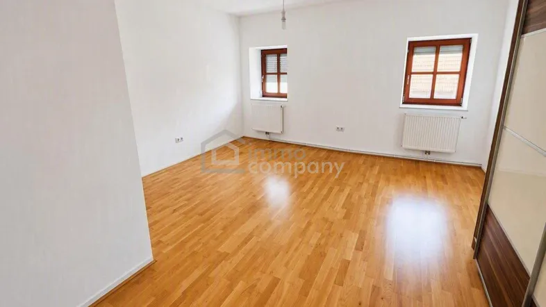 Helles, geräumiges Zimmer mit Parkettboden und zwei Fenstern, ideal als Schlaf- oder Wohnbereich.