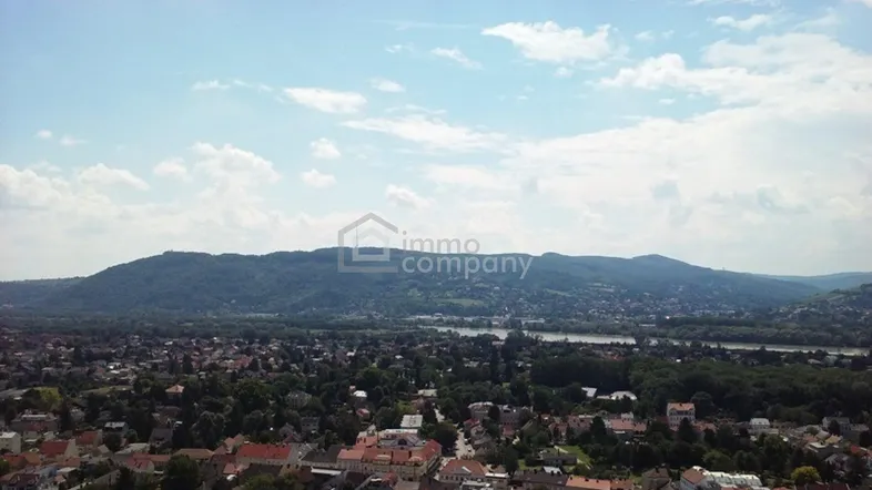 Luftaufnahme einer Stadt mit Bergen und einem Fluss im Hintergrund unter blauem Himmel.