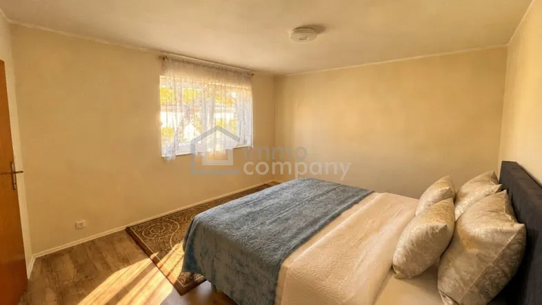 Helles Schlafzimmer mit Laminatboden und einem großen Bett, das zum Entspannen einlädt.