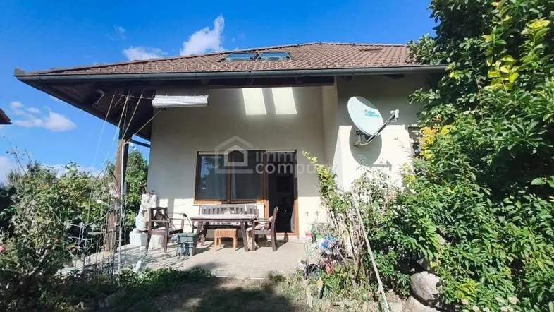 Gemütliche Terrasse mit Gartenmöbeln und üppiger Bepflanzung am Haus unter einem Satteldach.