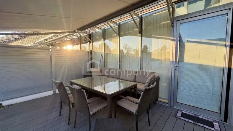 Möblierte Terrasse mit ausfahrbarer Markise und Blick auf die umliegende Landschaft bei Sonnenuntergang.
