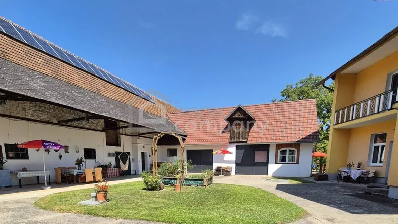 Ländliches Anwesen mit mehreren Gebäuden, einem begrünten Innenhof und Solaranlage auf dem Dach.