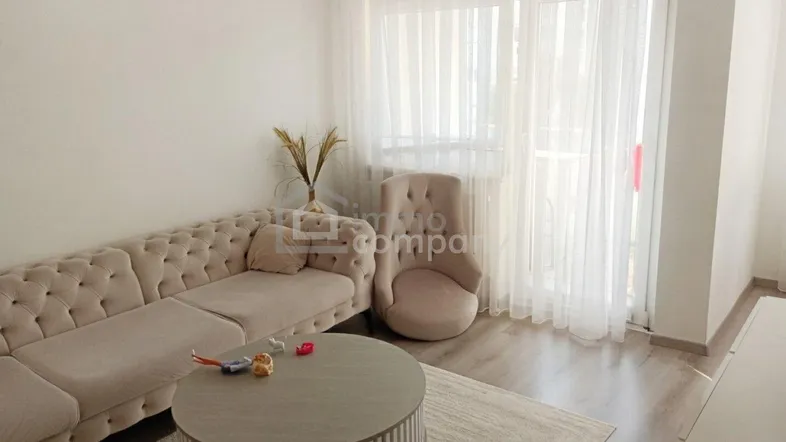 Helles Wohnzimmer mit beigem Sofa, Couchtisch und Zugang zum Balkon.