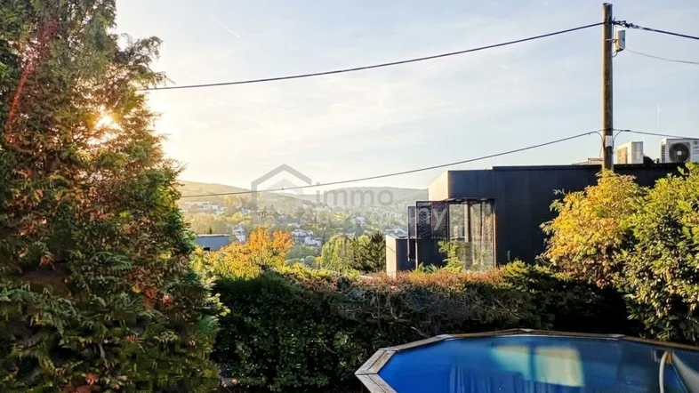 Gartenbereich mit Aufstellpool und weitem Blick über die hügelige Landschaft bei Sonnenuntergang.