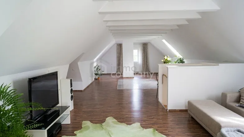 Heller, offener Wohnbereich im Dachgeschoss mit Holzboden und markanten Dachschrägen.