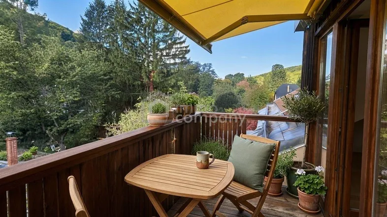 Gemütlicher Balkon mit Holzboden, Markise und weitem Blick ins Grüne.