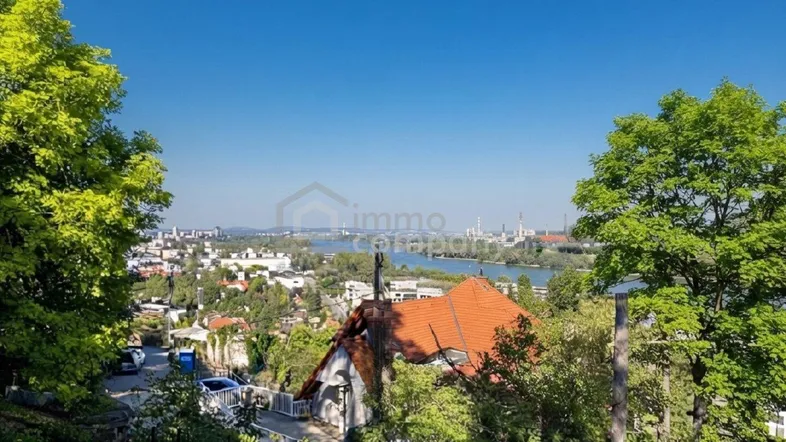 Panoramablick über die Stadt, den Fluss und die umliegende grüne Landschaft unter blauem Himmel.
